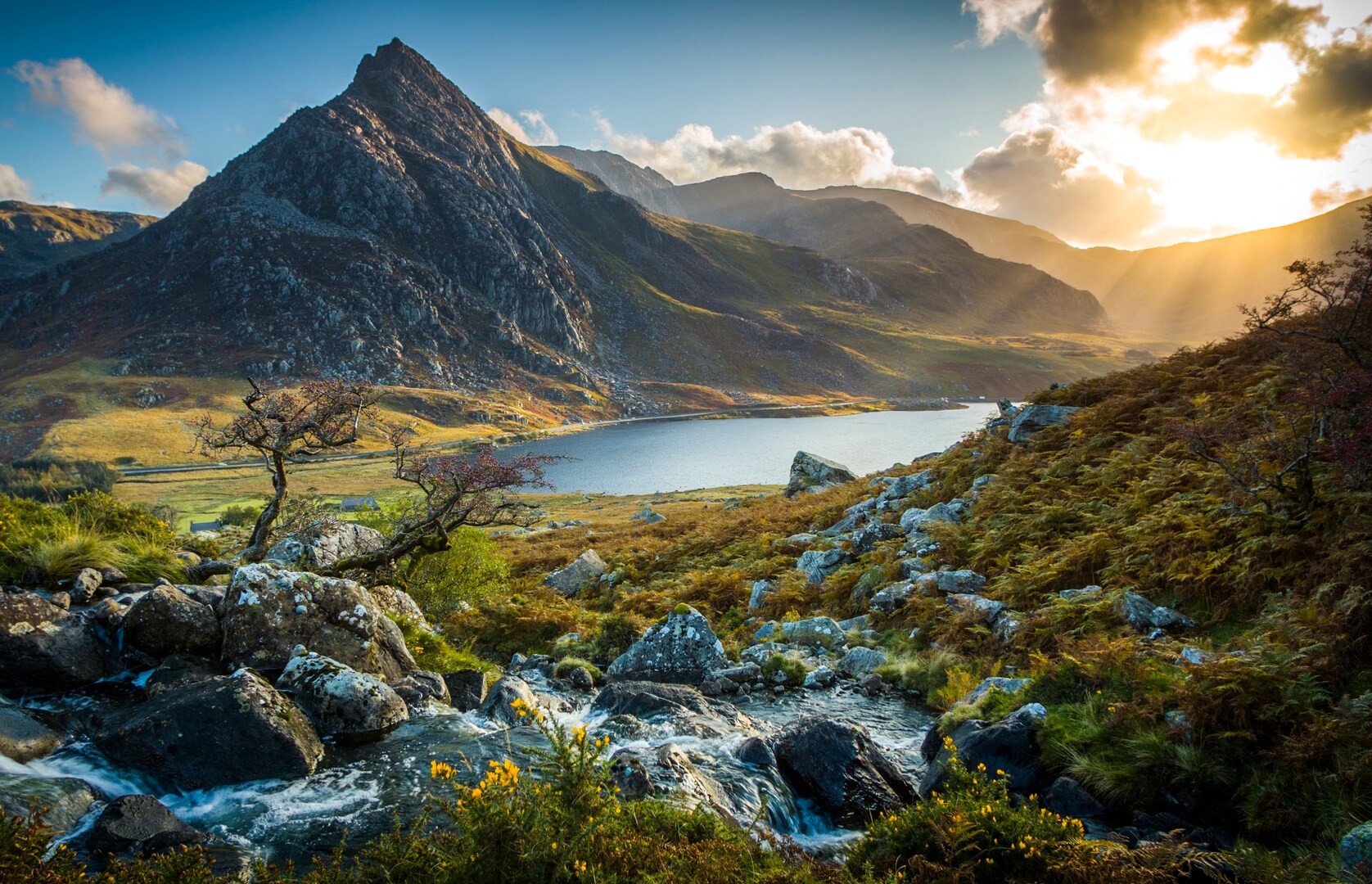 Snowdonia National Park in Wales: mountain stream, lake, and Tryfan mountain at sunset.