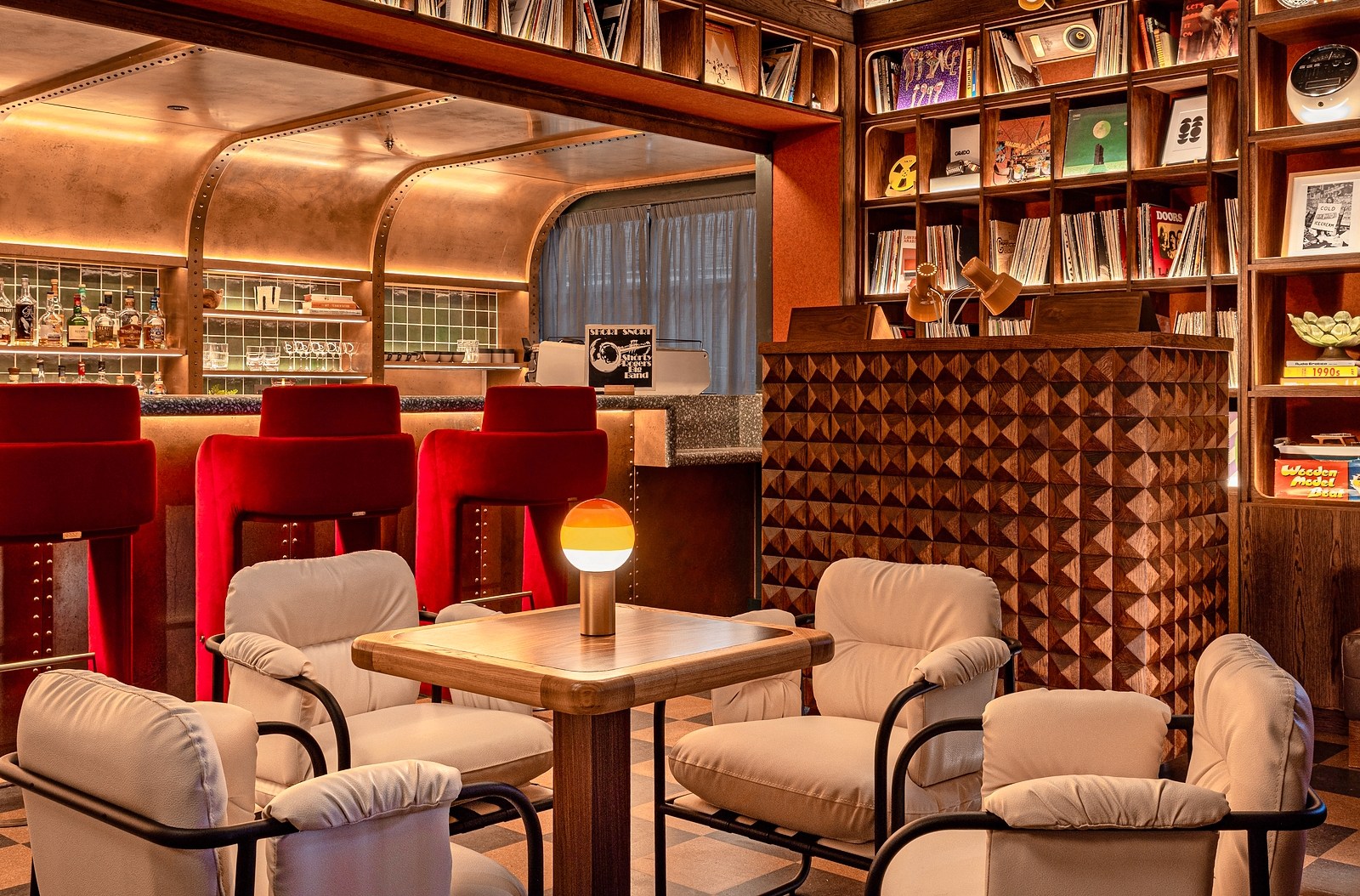 Bar area of the hotel featuring red bar stools and stylish armchairs.
