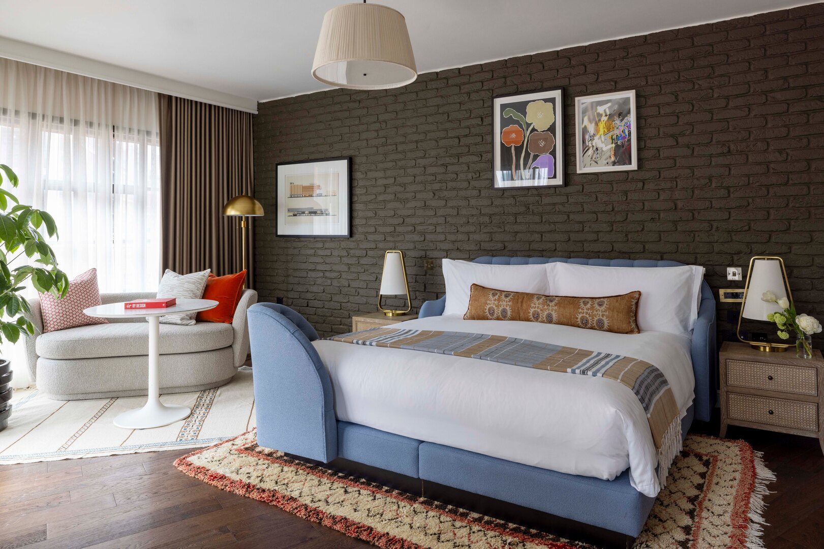Hotel room showcasing a blue bed, dark brick walls, and a patterned rug.
